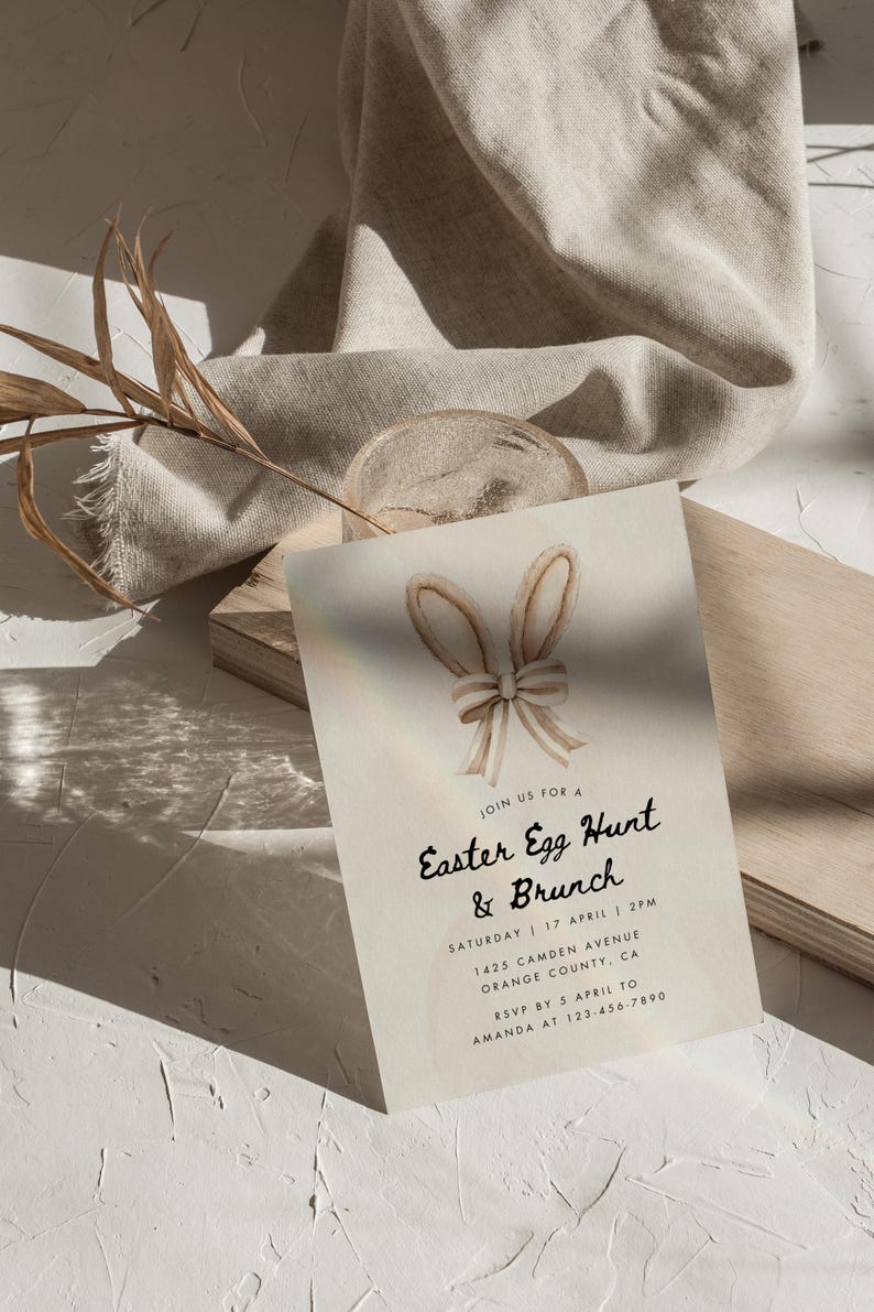 May include: A light beige invitation card with a watercolor illustration of bunny ears with a bow. The text on the card reads "Join us for a Easter Egg Hunt & Brunch, Saturday 17 April 2PM, 1425 Camden Avenue Orange County, CA, RSVP by 5 April to Amanda at 123-456-7890".