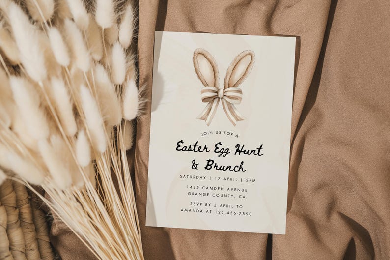 May include: A white card with brown bunny ears and a bow on top. The card is an invitation to an Easter Egg Hunt and Brunch on Saturday, April 17th at 2 PM. The address is 1425 Camden Avenue, Orange County, CA. RSVP by April 5th to Amanda at 123-456-7890.