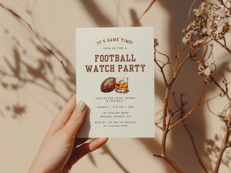 May include: A beige invitation card with brown text that reads "It's Game Time! Join us for a Football Watch Party". The card also includes a watercolor illustration of a football and a glass of whiskey.