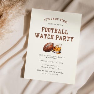 May include: A white card with brown text announcing a football watch party. The card features a watercolor illustration of a football and a glass of whiskey. The text reads "It's Game Time! Join us for a Football Watch Party. Join us for food, drinks & football. Sunday 9th Feb | 2pm. 147 Willow Drive, Orange County, CA. RSVP by 1st Feb to Monica at 123-456-7890."