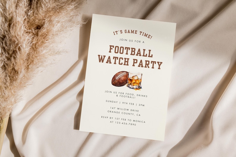 May include: A white card with brown text announcing a football watch party. The card features a watercolor illustration of a football and a glass of whiskey. The text reads "It's Game Time! Join us for a Football Watch Party. Join us for food, drinks & football. Sunday 9th Feb | 2pm. 147 Willow Drive, Orange County, CA. RSVP by 1st Feb to Monica at 123-456-7890."
