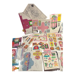 May include: A collection of vintage paper ephemera, including stickers, cutouts, and instructions. The items feature a pink, blue, and yellow color scheme with images of a doll, food, and other decorative elements. The word "Skipper" is visible.