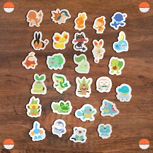 May include: A selection of colourful, die-cut stickers depicting various cartoon characters. The stickers, in various shapes and sizes with a white border, are arranged on a wooden surface. The characters are from a popular animated series.