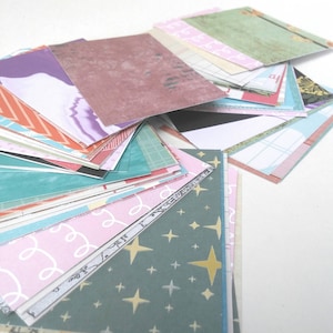 Puede incluir: Una pila de tarjetas de papel con patrones en varios colores, incluyendo rosa, azul, verde y rojo. Las tarjetas tienen diferentes dise&ntilde;os, como estrellas, espirales y patrones geom&eacute;tricos.