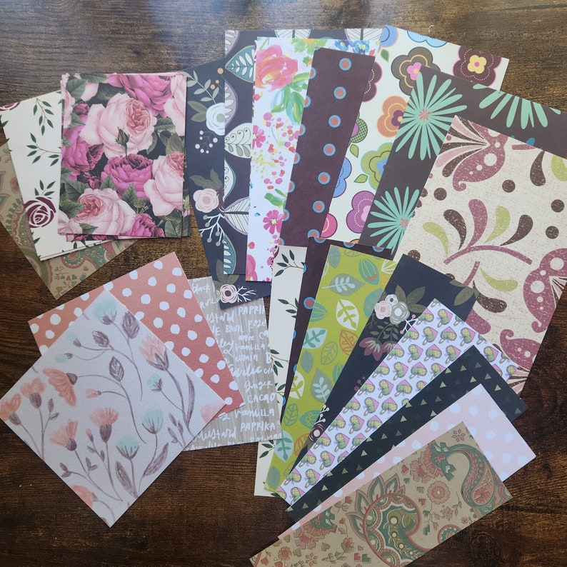 Pode incluir: Uma cole&ccedil;&atilde;o de folhas de papel retangulares com padr&otilde;es diversos, incluindo rosas cor-de-rosa, folhas verdes, bolinhas, paisley e ilustra&ccedil;&otilde;es bot&acirc;nicas. O sortido inclui v&aacute;rias paletas de cores como castanho escuro, creme, rosa claro e verde azeitona.