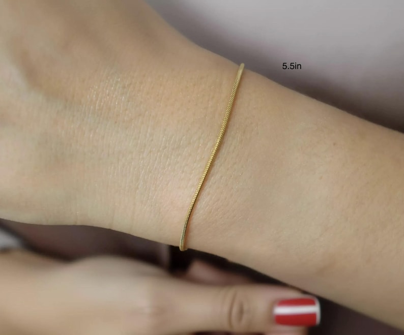 A close-up view of a person's wrist wearing a gold-colored bracelet.