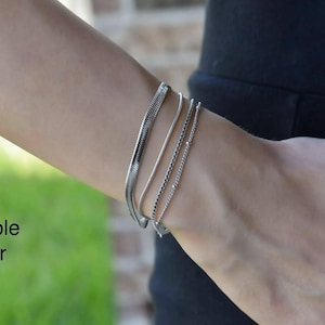 A close-up view of a person's wrist wearing multiple gold-colored bracelets.