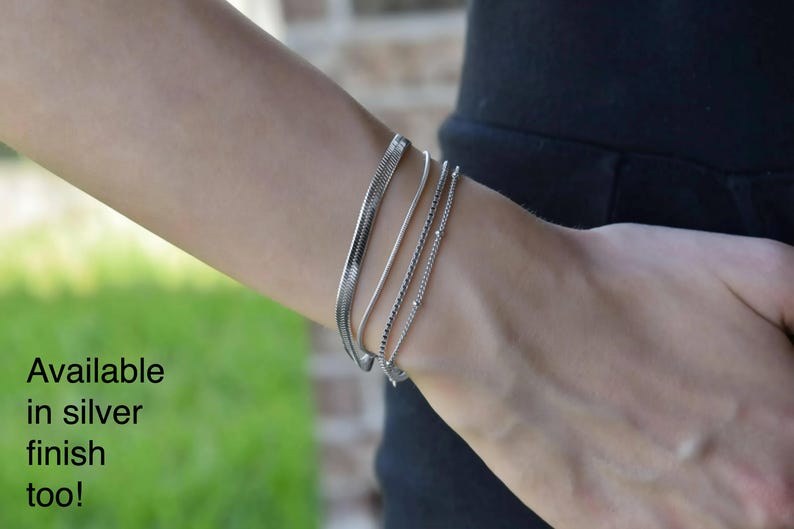 A close-up view of a person's wrist wearing multiple gold-colored bracelets.