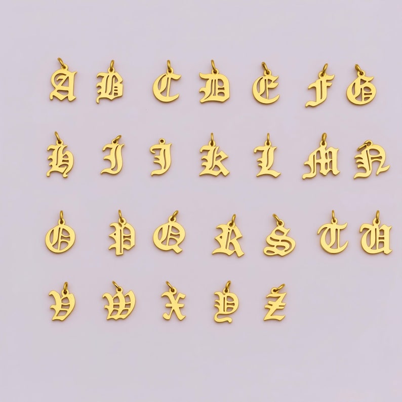 24 gold-colored alphabet charms arranged in a grid pattern, with each charm featuring a letter of the alphabet.