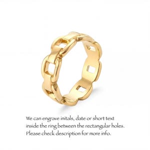 A gold-colored ring with a chain-link design, featuring a central hole surrounded by smaller holes.