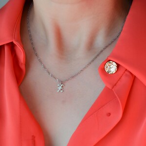 A close-up view of a person wearing a red blouse with a silver necklace and a small pendant.