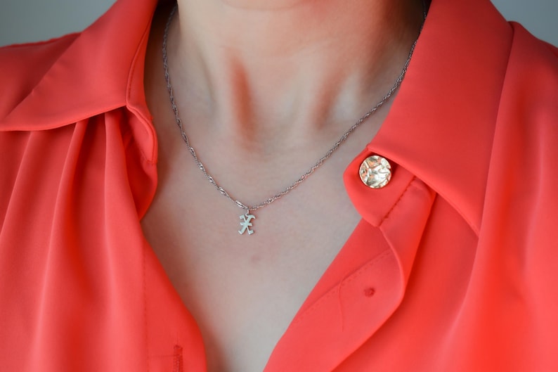 A close-up view of a person wearing a red blouse with a silver necklace and a small pendant.