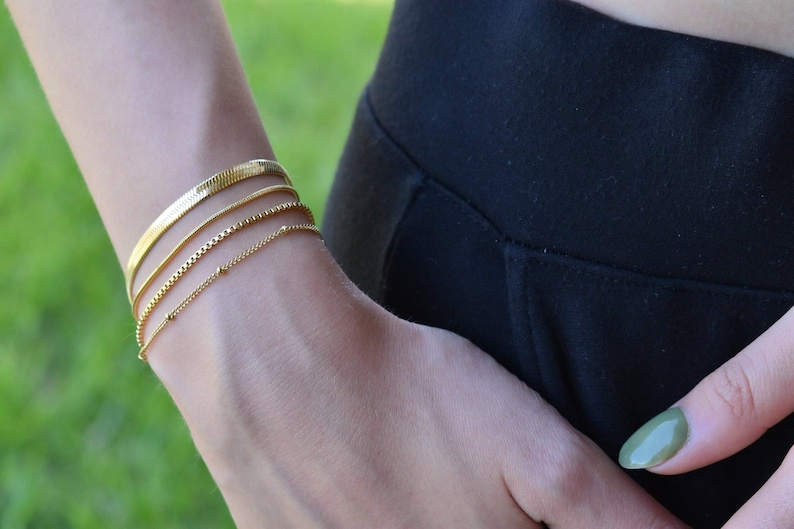 A close-up view of a person's wrist wearing multiple gold bracelets.