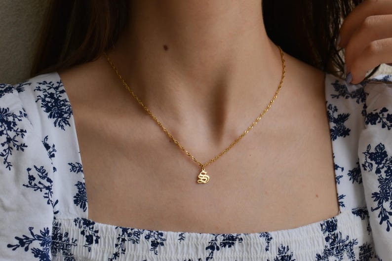A close-up view of a woman's neck and chest area, showing a gold necklace with a small pendant.