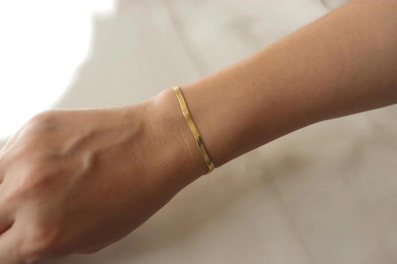 A gold bracelet is worn on a person's wrist.
