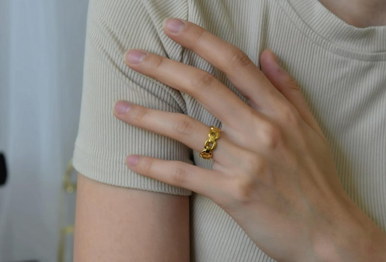 A close-up of a person's hand wearing a gold ring on the ring finger.