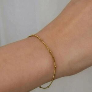 A close-up view of a person's wrist wearing a gold bracelet and ring.