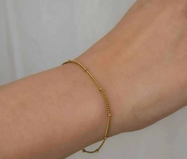 A close-up view of a person's wrist wearing a gold bracelet and ring.