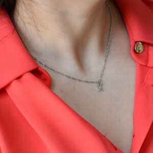 A close-up view of a person wearing a bright red blouse with a necklace and buttons.