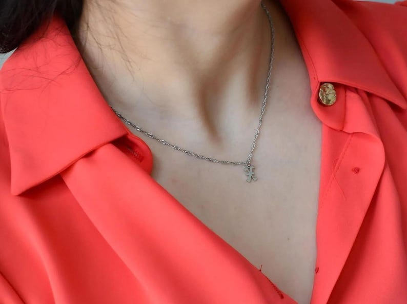 A close-up view of a person wearing a bright red blouse with a necklace and buttons.