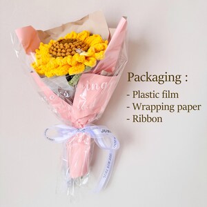 May include: A crocheted sunflower bouquet wrapped in pink tissue paper and tied with a white ribbon. The bouquet is packaged in plastic film and includes a note that says "Just You".