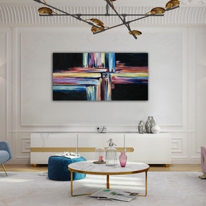 May include: Abstract painting with colorful stripes and lines on a black background. The painting is hanging on a white wall in a living room setting.