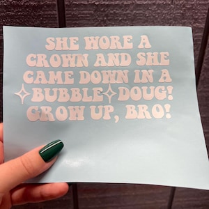 May include: White vinyl sticker with the text "SHE WORE A CROWN AND SHE CAME DOWN IN A BUBBLE DOUG! GROW UP, BRO!" in a retro font style.