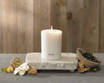 Può includere: Candela bianca su un vassoio di marmo bianco con fiori secchi e una piccola ciotola di foglie di tè verde.