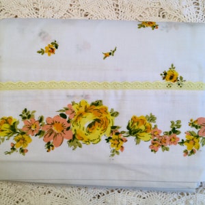 May include: White cotton fitted sheet with a yellow and peach floral pattern. The sheet has a delicate lace trim along the top edge.