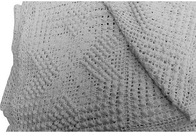 May include: White crocheted baby blanket with a diamond pattern. The blanket is made of soft, lightweight yarn and is perfect for keeping a baby warm and cozy.