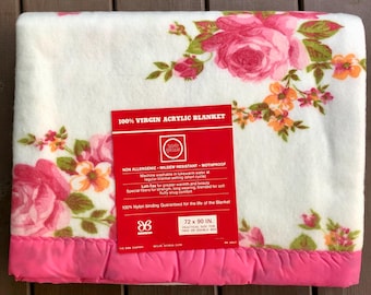 May include: A white acrylic blanket with a pink floral pattern. The blanket is 100% virgin acrylic and is non-allergenic, mildew resistant, and mothproof. It is machine washable and measures 72 inches by 90 inches.