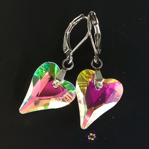 Könnte beinhalten: Ein Paar silberne herzförmige Ohrringe mit schimmernden Kristall-Akzenten. Die Kristalle haben einen Regenbogeneffekt mit Schattierungen von Rosa, Grün und Gelb.