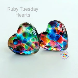 May include: Two colorful glass heart-shaped ornaments with a mosaic pattern of red, blue, green, yellow, and orange. The hearts are on a white background.
