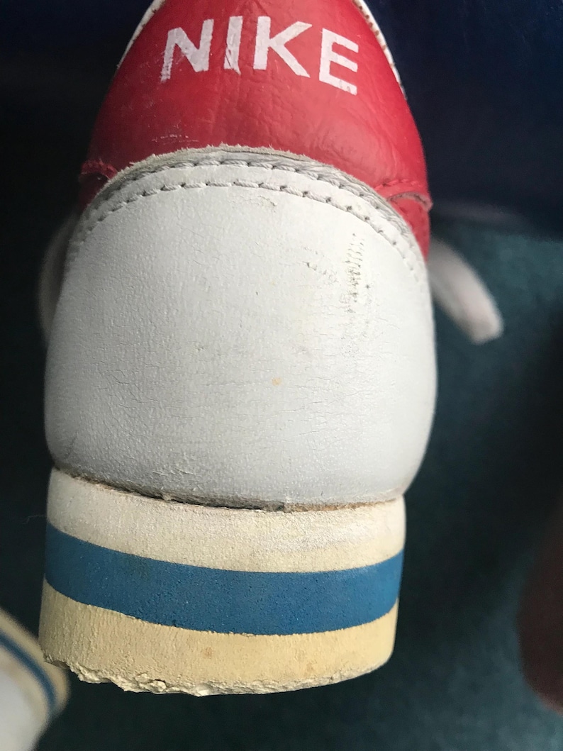 May include: Close-up of a white leather Nike shoe with a red leather upper and blue and white trim. The Nike logo is visible on the red upper.