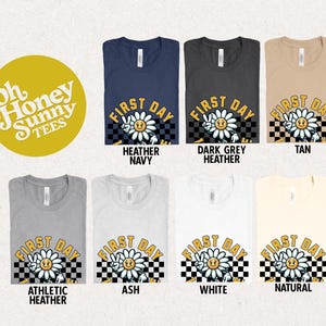May include: A set of ten t-shirts featuring a daisy with a peace sign and the text "First Day" in a retro font. The shirts are available in a variety of colors, including heather navy, dark grey heather, tan, athletic heather, ash, white, and natural.