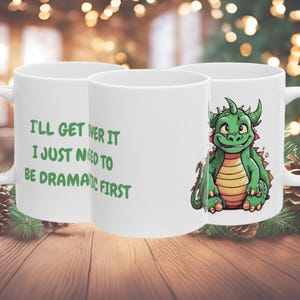 May include: Three white ceramic mugs with green text and a green cartoon dragon design. The mug on the left says "I'll get over it I just need to be dramatic first".