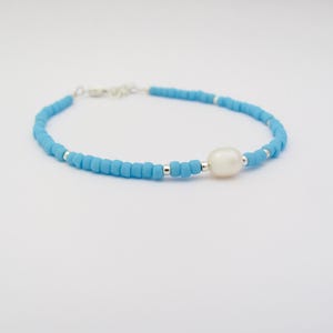 May include: A delicate blue beaded bracelet with a single white pearl charm.