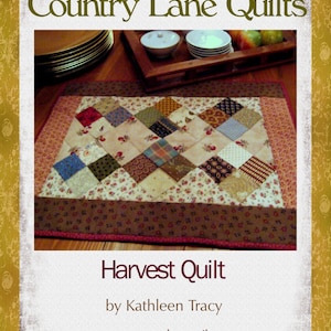 May include: A brown and tan patchwork quilt with a diamond pattern. The quilt is called "Harvest Quilt" and is by Kathleen Tracy. The website for Country Lane Quilts is shown at the bottom of the image.