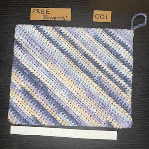 Puede incluir: Un agarrador de ganchillo hecho a mano en tonos de azul, crema y lavanda, con un patrón de rayas diagonales. Tiene un lazo para colgar y el texto "FREE Shipping!" es visible. Una regla está en la parte inferior.