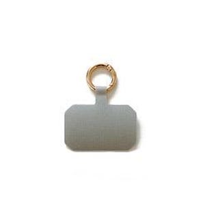 May include: A rectangular grey phone tether tab with rounded corners and a gold-toned metal ring attached to the top. The tab features a smooth, solid-coloured surface and a small vertical extension that connects the main body to the circular ring.