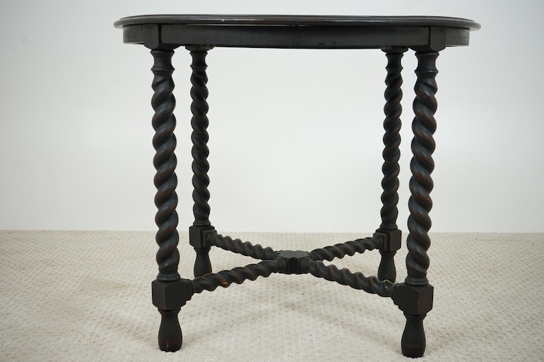 May include: Dark brown antique side table with a round top and four spiral-turned legs. The legs are connected by an X-shaped stretcher near the base. The table is made of wood and has a classic design.