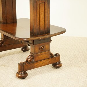 May include: A detailed view of a dark brown wooden table, featuring a rectangular top and elaborately carved legs. The table's surface is polished, and the legs have decorative elements and rounded feet. The table is likely an antique.