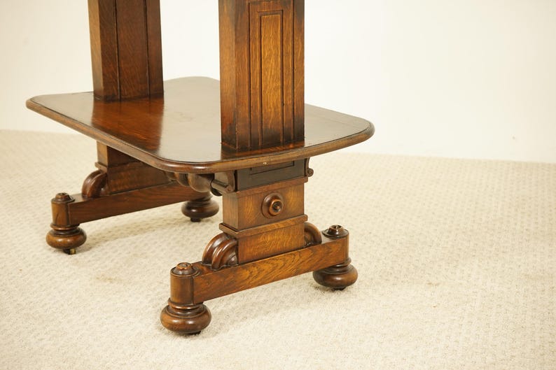 May include: A detailed view of a dark brown wooden table, featuring a rectangular top and elaborately carved legs. The table's surface is polished, and the legs have decorative elements and rounded feet. The table is likely an antique.