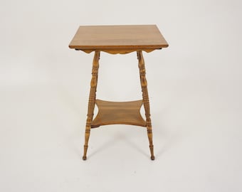 May include: A small, antique wooden side table with a square top and a lower shelf. The table has ornate, carved legs and a natural wood finish. The table is approximately 61 cm tall.
