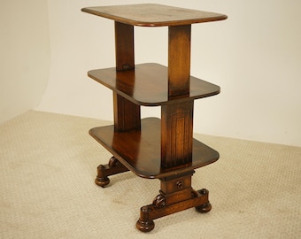 May include: A three-tiered, dark wood side table with a rectangular top and two lower shelves. The table has a decorative base with carved details and is supported by four rounded feet. The wood has a glossy finish.
