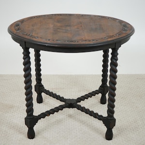 Peut inclure: Table d'appoint antique marron foncé, avec un plateau rond orné de motifs sculptés. Elle possède quatre pieds torsadés et une base en forme de X. La table mesure environ 61 cm de haut et 61 cm de large, un meuble classique.