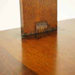 May include: Close-up of a wooden table with a dark, glossy finish. The table has a rectangular support piece attached to the tabletop. The wood grain is visible, and the surface reflects light.