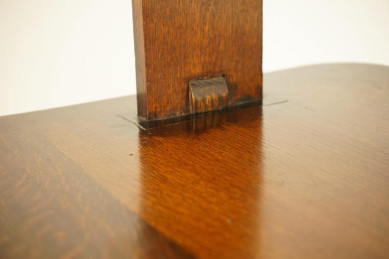 May include: Close-up of a wooden table with a dark, glossy finish. The table has a rectangular support piece attached to the tabletop. The wood grain is visible, and the surface reflects light.