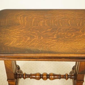 May include: An antique wooden table with a rectangular top and decorative legs. The table is made of dark brown wood with a visible wood grain pattern. The table's top is approximately 61 cm long and 46 cm wide.