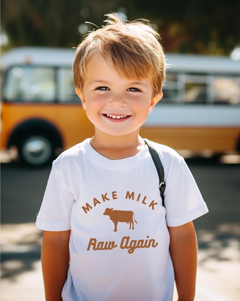 Puede incluir: Una camiseta blanca con un gr&aacute;fico marr&oacute;n que dice "Make Milk Raw Again" con una silueta de una vaca.